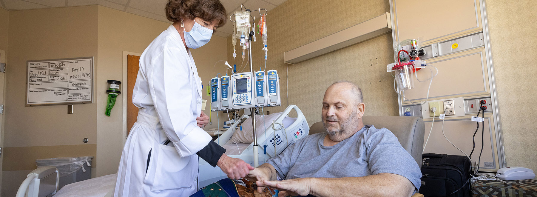 Staff member checking a bone marrow transplant patient's vital signs.